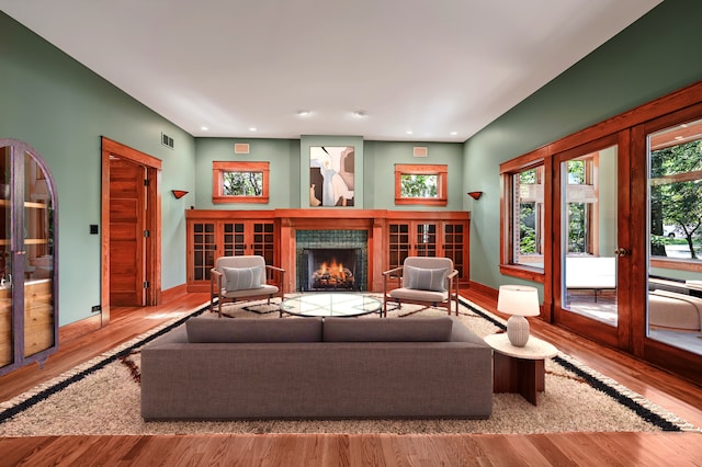 living room with a tiled fireplace and light wood-type flooring