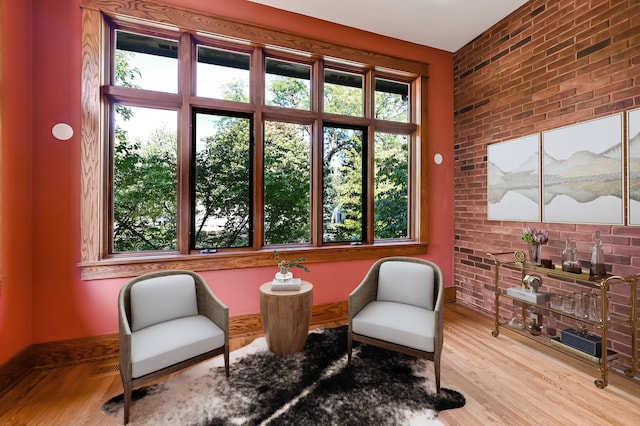 living area with brick wall and light wood-type flooring