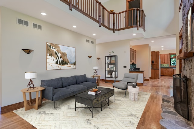 living room featuring a fireplace, a towering ceiling, and light hardwood / wood-style flooring