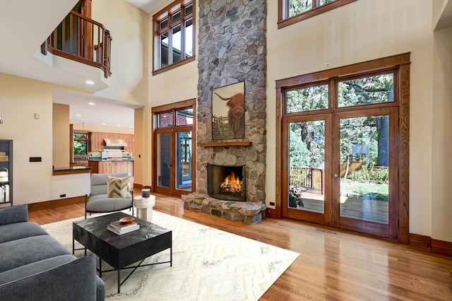 living room with a fireplace, light wood-type flooring, and a high ceiling