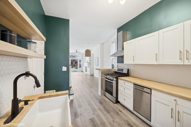 kitchen featuring white cabinetry, sink, wall chimney exhaust hood, stainless steel appliances, and decorative backsplash