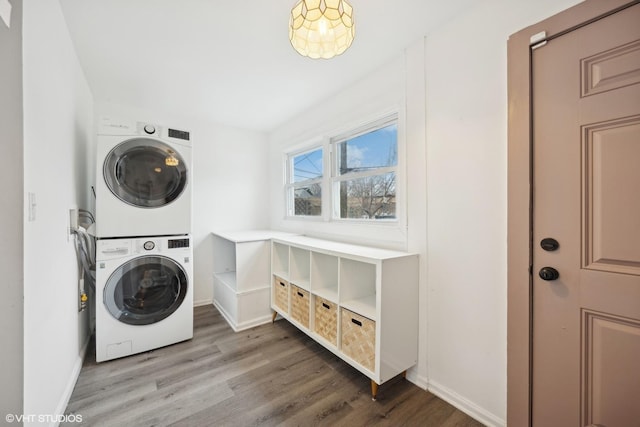 clothes washing area with hardwood / wood-style flooring and stacked washer / drying machine