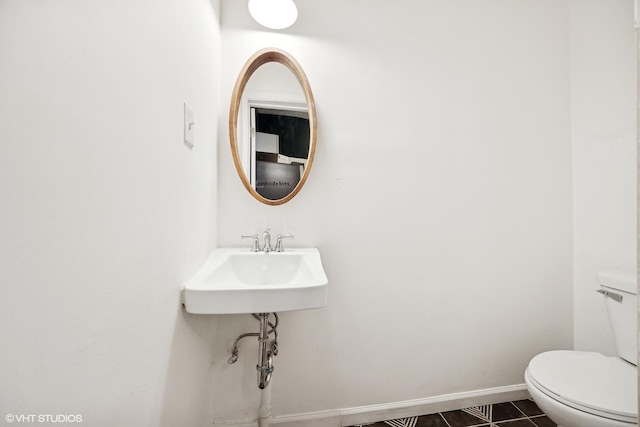 bathroom featuring toilet, tile patterned floors, and sink