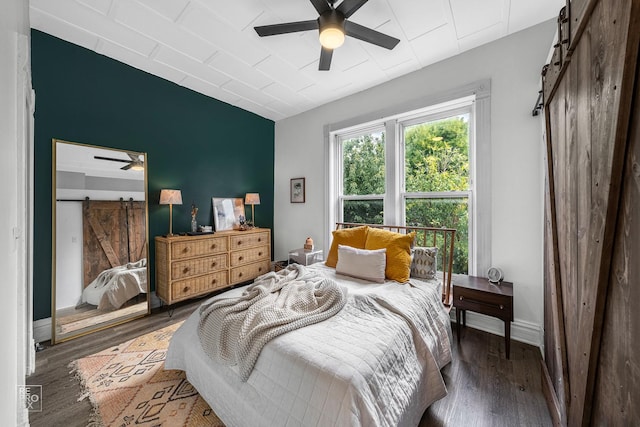 bedroom featuring ceiling fan, a barn door, and dark hardwood / wood-style floors