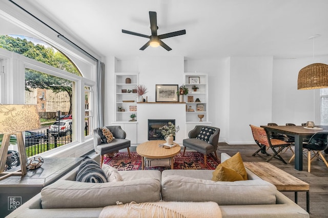 living room with hardwood / wood-style flooring, plenty of natural light, ceiling fan, and built in shelves