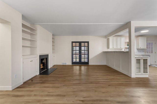 unfurnished living room with hardwood / wood-style floors and french doors