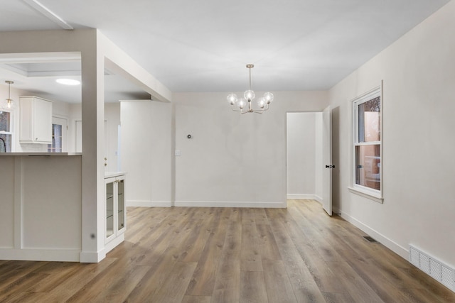 spare room featuring hardwood / wood-style flooring and an inviting chandelier