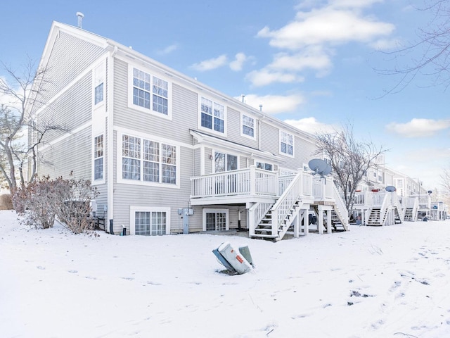 snow covered back of property featuring a deck