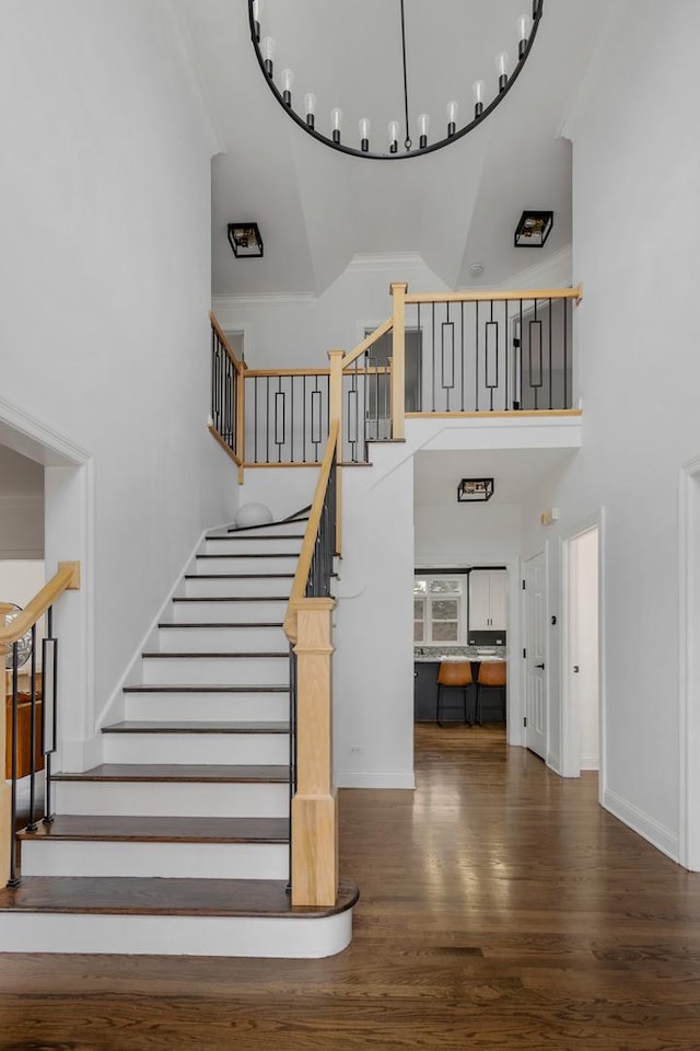 stairway with hardwood / wood-style floors, crown molding, and a high ceiling