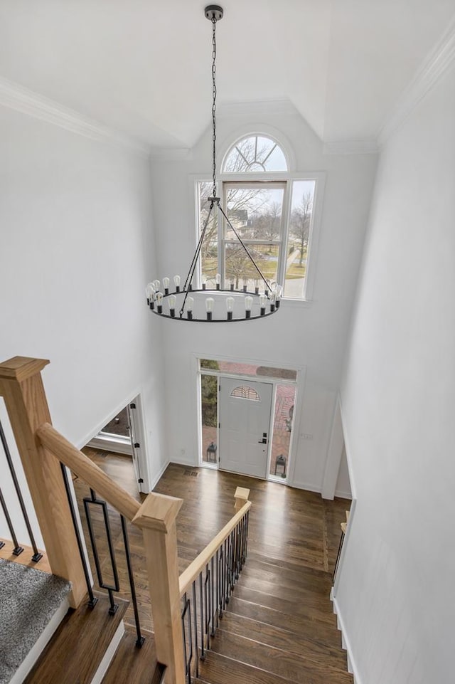 stairs with hardwood / wood-style floors, ornamental molding, a chandelier, and a high ceiling