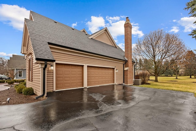 view of side of home with a garage and central air condition unit