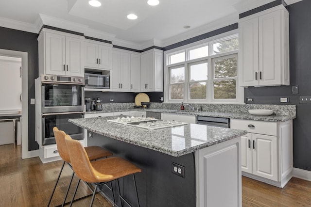 kitchen with light stone counters, stainless steel appliances, white cabinets, and a kitchen island