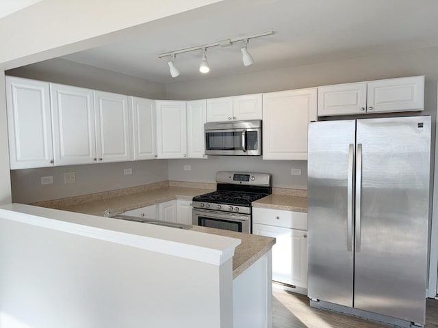 kitchen featuring kitchen peninsula, white cabinetry, sink, and stainless steel appliances