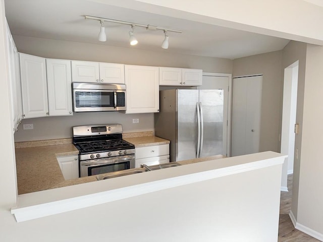 kitchen with sink, light wood-type flooring, white cabinetry, kitchen peninsula, and stainless steel appliances