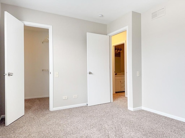 unfurnished bedroom featuring light colored carpet, a spacious closet, and a closet