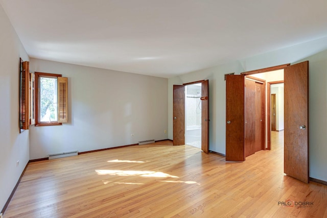 unfurnished room with light hardwood / wood-style flooring and a baseboard heating unit