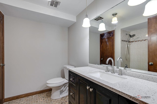 bathroom with vanity, toilet, and a tile shower