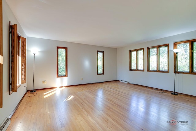 unfurnished room with light hardwood / wood-style floors and a baseboard heating unit