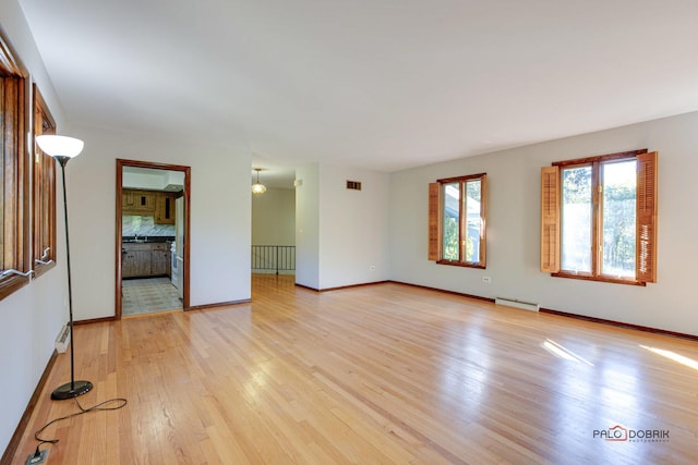 spare room with baseboard heating and light hardwood / wood-style flooring