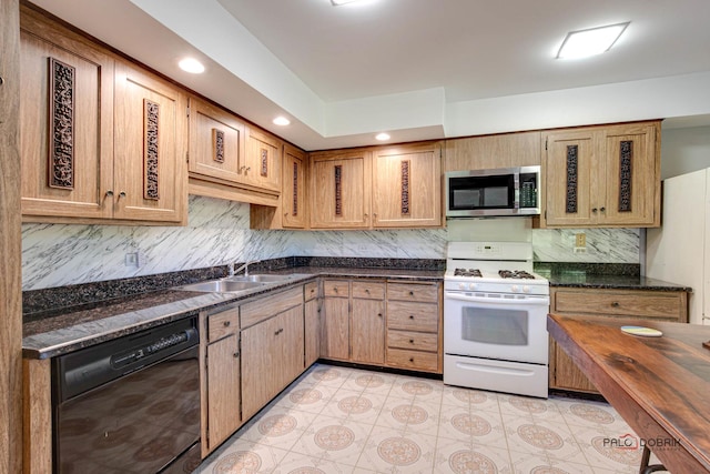 kitchen featuring dark stone counters, sink, white range with gas stovetop, and black dishwasher