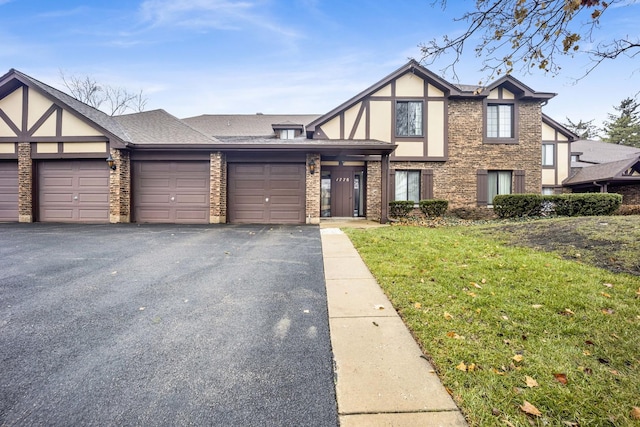 tudor home with a front yard and a garage