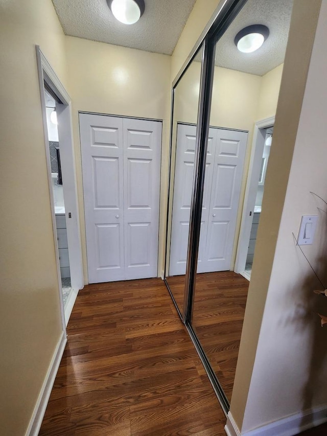 hall featuring dark wood-type flooring and a textured ceiling