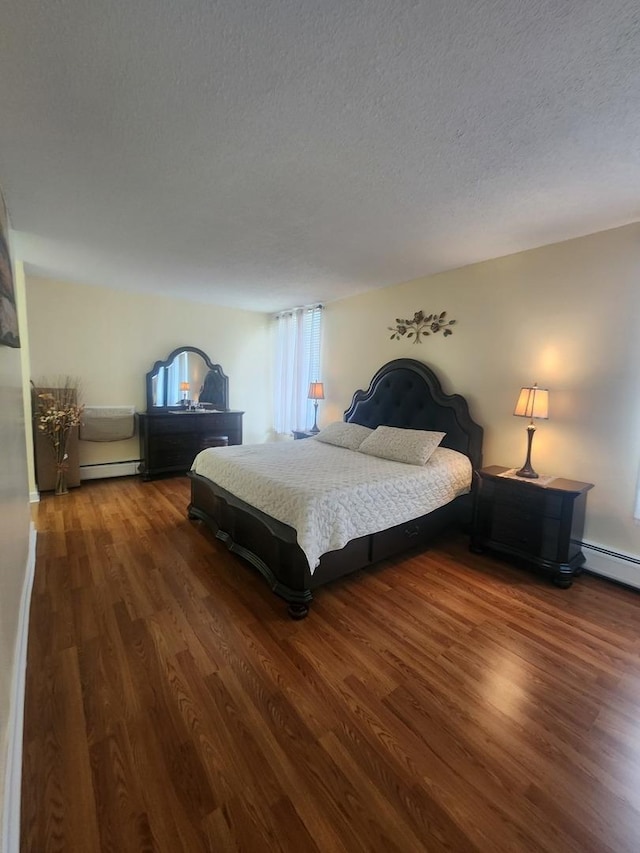 bedroom featuring dark hardwood / wood-style floors, baseboard heating, and a textured ceiling