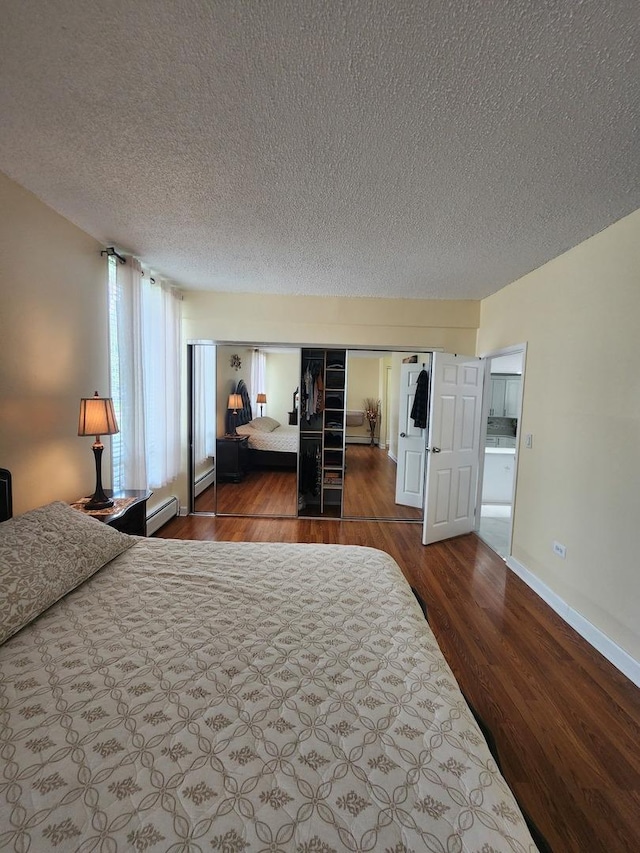 bedroom featuring hardwood / wood-style floors, a textured ceiling, and baseboard heating