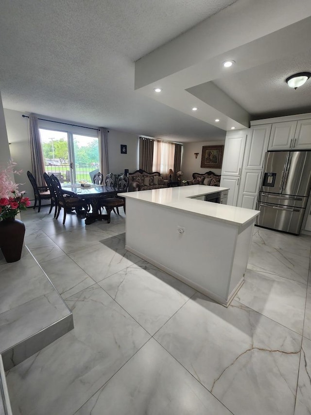 kitchen with white cabinetry, stainless steel fridge, a kitchen island, and a textured ceiling