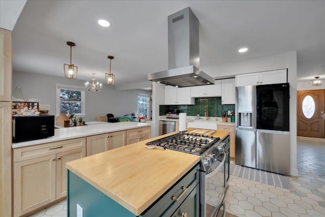 kitchen featuring appliances with stainless steel finishes, backsplash, ventilation hood, a notable chandelier, and a kitchen island