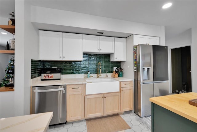 kitchen with decorative backsplash, stainless steel appliances, sink, light brown cabinets, and light tile patterned floors