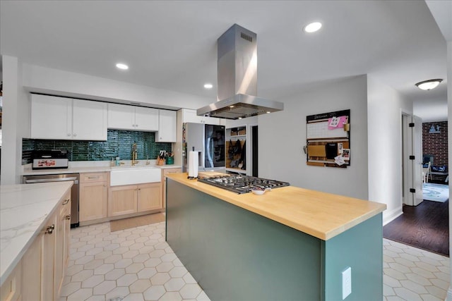 kitchen with light brown cabinetry, island range hood, stainless steel appliances, sink, and a kitchen island