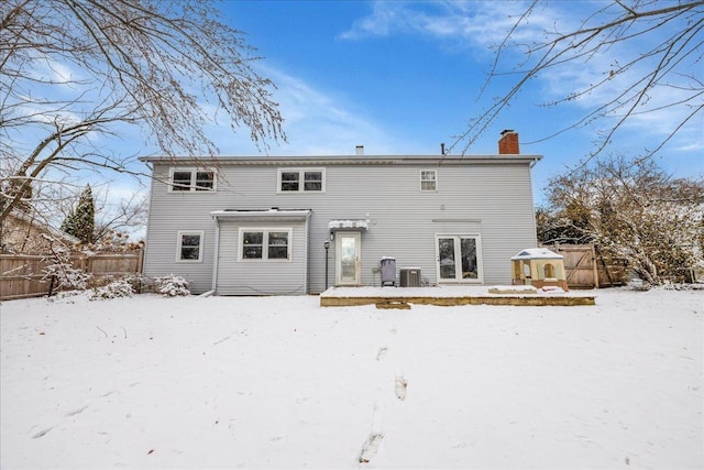 snow covered house with cooling unit and a deck