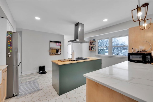 kitchen with green cabinetry, light stone countertops, appliances with stainless steel finishes, decorative light fixtures, and island exhaust hood