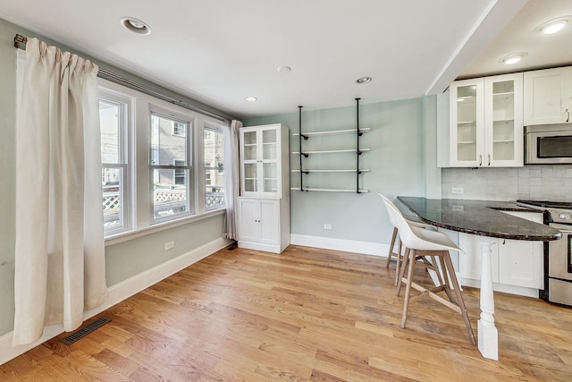 unfurnished dining area with light wood-style floors, recessed lighting, visible vents, and baseboards