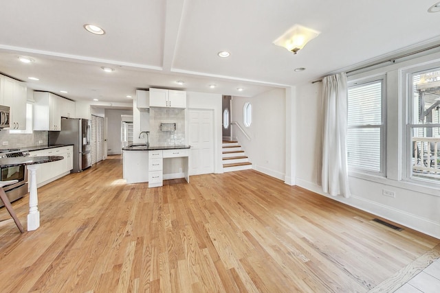 living room with light wood finished floors, baseboards, stairs, and visible vents