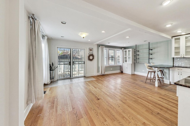 unfurnished living room with baseboards, recessed lighting, and light wood-style floors