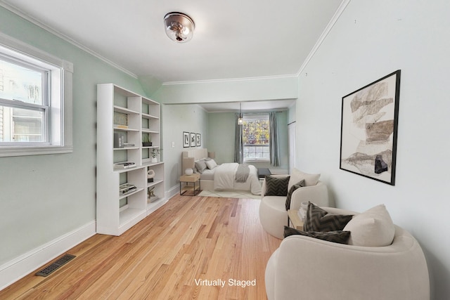 living area with light wood-type flooring, baseboards, visible vents, and ornamental molding