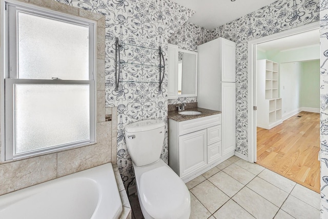 full bathroom with wallpapered walls, toilet, a bathing tub, tile patterned floors, and vanity