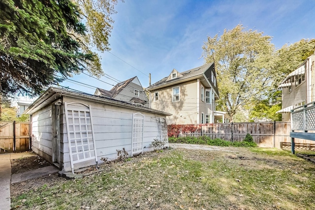 rear view of house with a lawn, an outdoor structure, and fence