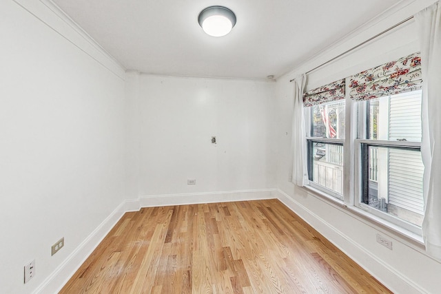 unfurnished room with crown molding, light wood-style flooring, and baseboards