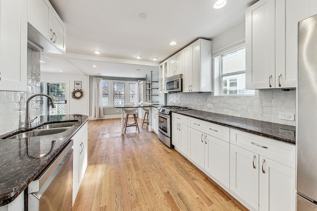 kitchen featuring plenty of natural light, white cabinets, light wood-style flooring, appliances with stainless steel finishes, and a sink