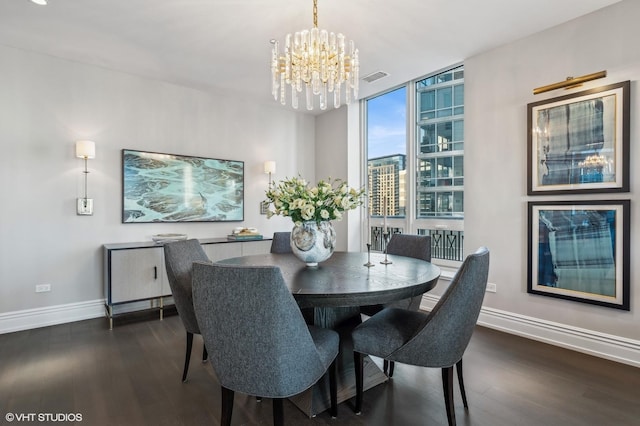 dining space with dark wood-type flooring, visible vents, a notable chandelier, and baseboards