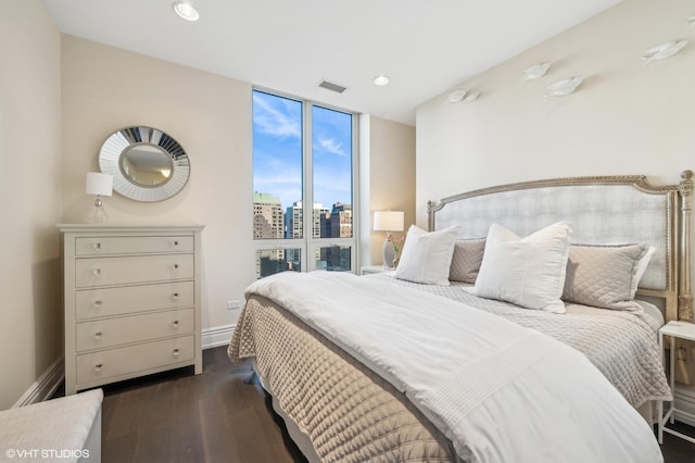 bedroom featuring a view of city, dark wood finished floors, recessed lighting, visible vents, and baseboards