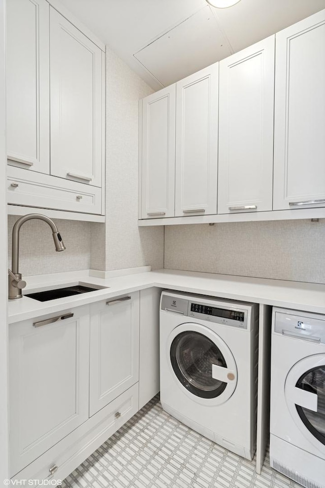 laundry area featuring cabinet space, separate washer and dryer, a sink, and light floors