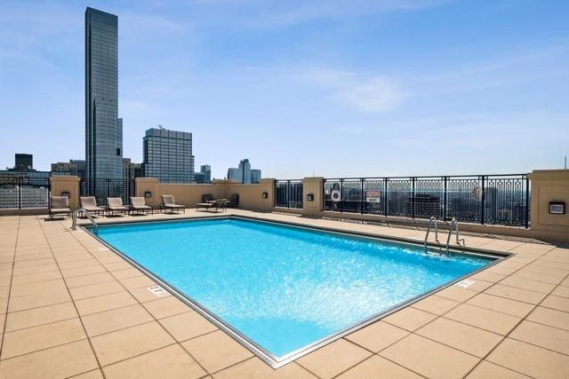 community pool with a view of city, a patio, and fence