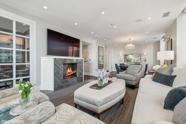 living room featuring recessed lighting, wood finished floors, a high end fireplace, visible vents, and an inviting chandelier