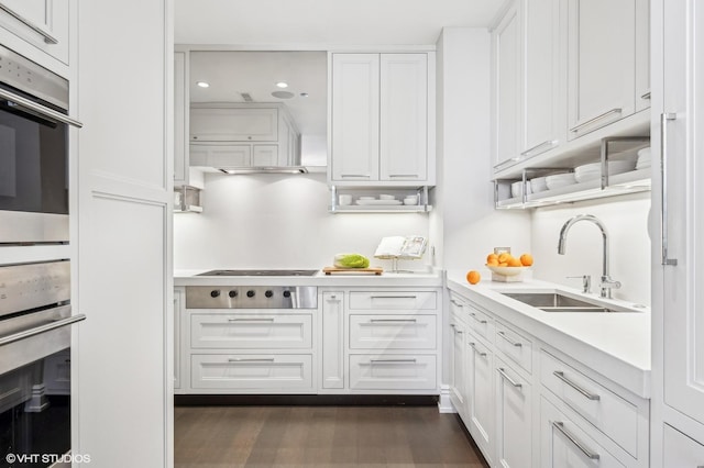 kitchen with appliances with stainless steel finishes, light countertops, white cabinetry, a sink, and recessed lighting