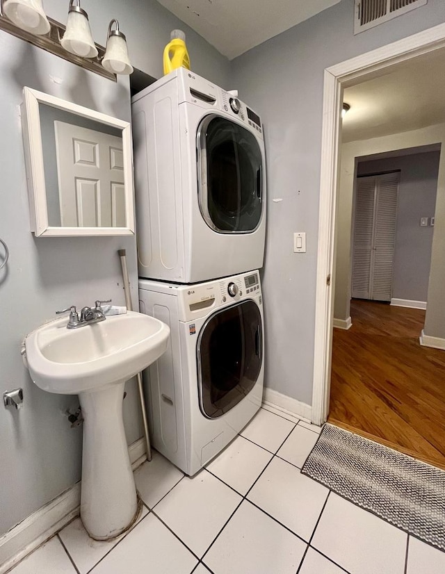 clothes washing area with light tile patterned floors and stacked washing maching and dryer