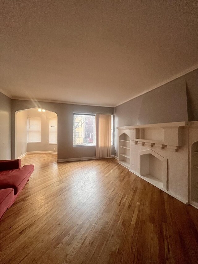7628 S Essex Ave Unit 1N, Chicago, IL 60649 - unfurnished living room featuring wood finished floors, arched walkways, and crown molding